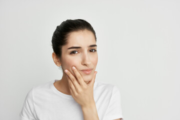 woman in white t-shirt holding face toothache discontent