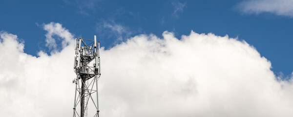 Bottom perspective pov of modern metal steel mobile 5g network wireless telecom tower against clear blue sky background on bright day. Microwave signal broadband equipment base line station mast - Powered by Adobe