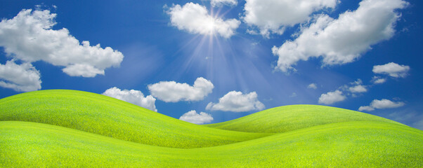 Obraz premium Panorama landscape of green grass field on a hill with beautiful blue sky with clouds. ecology and natural background concept.