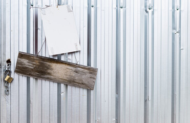 Old wooden sign and white plastic board hanging on metal sheet wall, construction industry, blank sing at construction site
