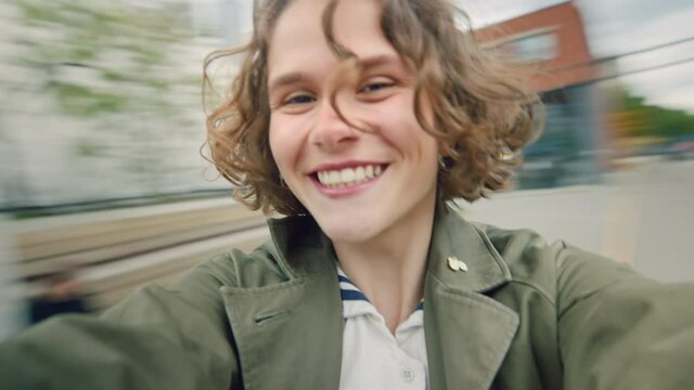 Happy authentic young woman with curly short hair spins around. Hold camera to make selfie or have fun with best friend. Real feelings and emotions of happiness and joy