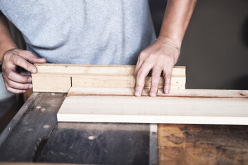 Woodworking practitioners use saw blades to cut wood pieces to assemble and build wooden tables for their clients.