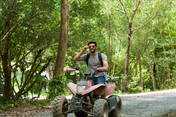 Young man driving off road adventure with happy and smiling. Man riding on ATV bike or quad bike on...
