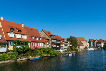 Bamberg Germany 08-08-2019 - Picturesque view of the medieval buildings along the Regnitz River with old barge, moored boats and on the river shore in UNESCO Heritage city Bamberg, Bavaria, Germany.