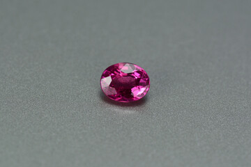 Natural earth mined unheated, untreated oval faceted rich red color loose small ruby gemstone setting for making jewelry from Winza, Tanzania. Gray patterned backgound. Gemology, mineralogy  theme.