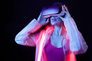 Woman in futuristic costume. Girl in glasses of virtual reality. Augmented reality game, future technology, AI concept. VR. Neon red light.