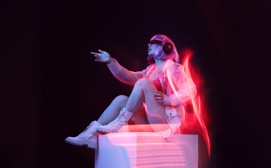Woman in futuristic costume. Girl in glasses of virtual reality. Augmented reality game, future technology, AI concept. VR. Neon red light.