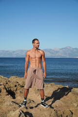 a young guy is walking along a rocky beach near the sea