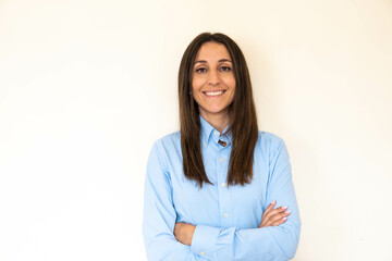 Young and attractive woman looking corporative with a shirt smiling at the camera, looking professional and ready to do bussiness with a white background. Wearing a blue shirt. Latin woman business.