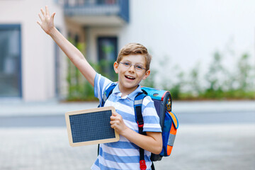 Happy little kid boy with backpack or satchel. Schoolkid on the way to school. Healthy adorable...
