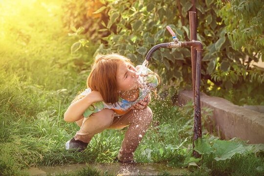 Cute Girl Drinking Water From The Tap Outdoors