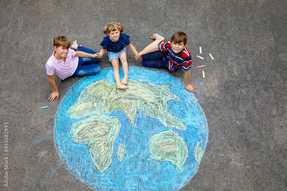 Wall mural little preschool girl and two school kids boys with earth globe painting with colorful chalks on gro