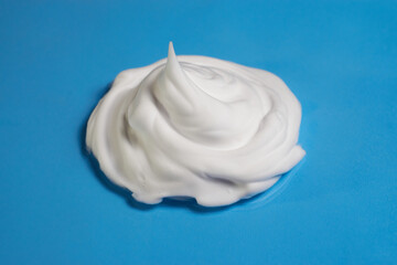 White shaving foam on a blue background