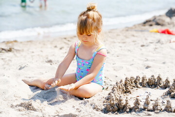 Little preschool girl playing with sand toys on the beach. Cute happy toddler child on family vacations on the sea. Active child having fung on Baltic Sea. Outdoor activity for children