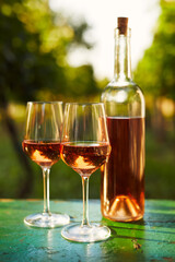Two glasses and a bottle of rosé wine on an old wooden table