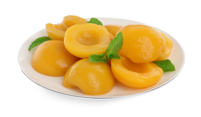 Plate with canned peach halves and mint leaves isolated on white