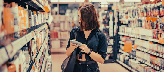 Fototapeta na wymiar Young woman choosing care cosmetic in a supermarket. shopping