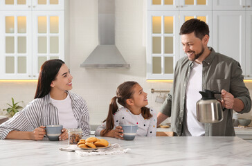 Happy family having breakfast at table in kitchen. Adoption concept