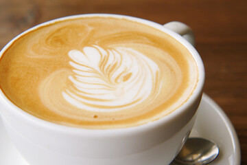 a cup of late coffee with flower shape design on top at cafe 
