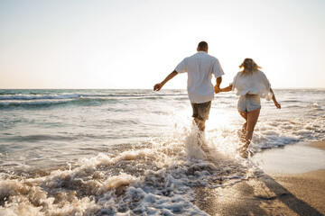 Young beautiful couple walking on beach near sea