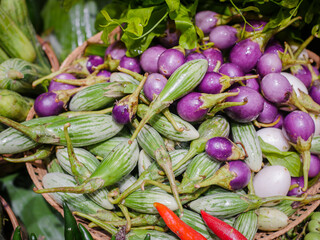 Various types of eggplants are sold on vegetable stands.