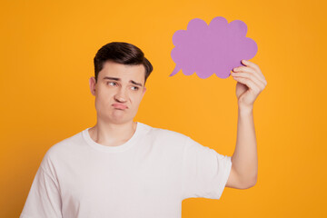 Portrait of upset displeased guy hand hold creative cloud look empty space on yellow background