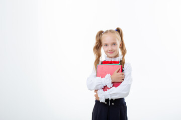 Fototapeta premium little girl in a school uniform holds a book and an apple isolated on a white background