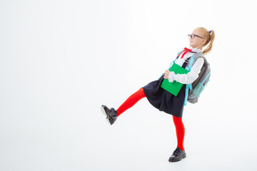 a little schoolgirl girl in a school uniform holds a book isolated on a white background