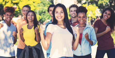 Happy south american female student with group of cheering young adults