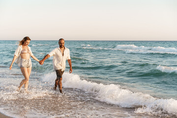 Fototapeta na wymiar Young beautiful couple walking on beach near sea