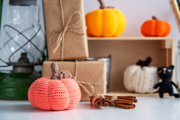 Autumn decor. Crocheted orange pumpkin, cinnamon sticks, gifts in craft paper.