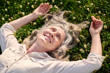 Happy woman lying on green lawn