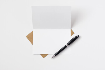 Open blank card with brown envelope and black and silver pen