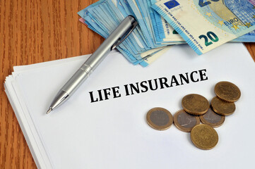 Concept d'assurance vie avec de l'argent en cash et un stylo posés sur un contrat en anglais