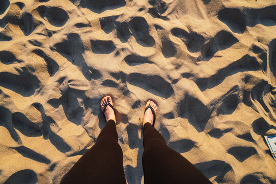woman legs in the sand on the beach with sunset light