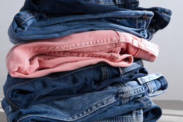a pile of blue and pink jeans on a gray background. Close up