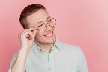 Photo of young handsome man happy positive smile hands touch glasses look empty space isolated over pink color background