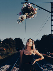 woman walking on railroad with a flying bouquet