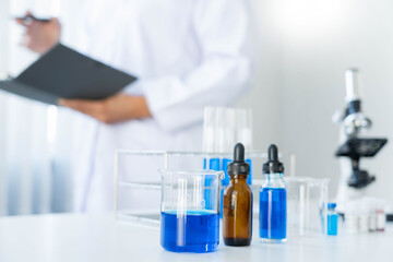 scientists researching in laboratory in white lab coat, gloves analysing, looking at test tubes...