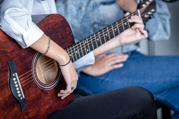 Fototapeta premium Close up Two women fingers holding mediator with a Guitar recording a song in recording studio
