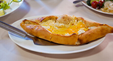 Food. Traditional khachapuri with cheese and egg. Khachapuri on a plate on a served table close-up.