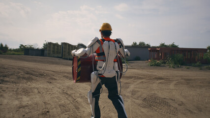 Man in exoskeleton carrying barrel on construction site