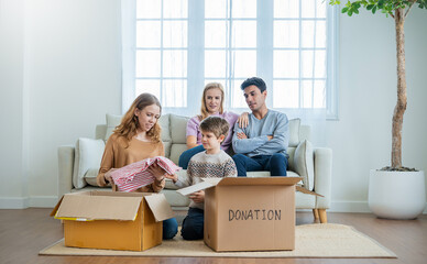 Portrait of volunteer caucasian family couple of parents, daughter and son putting belonging in cardboard box. Family leisure activities donation boxes, happy together concept.
