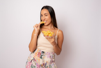 Young beautiful woman holding bowl of chips potatoes over white background with surprise face