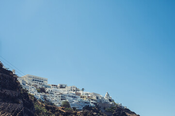 Fototapeta na wymiar Scenic cityscape of Thira. city on the hill. White architecture. Santorini island, Greece. Luxury tourism. Caldera sea view.