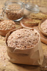 Paper bag with wheat bran on wooden table