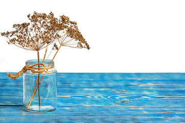 dry dill seeds in a glass jar on a blue wooden table isolated on a white background