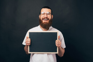 Happy to announce this. Smiling man is holding a black board.