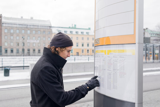 Young man checking timetable at bus stop