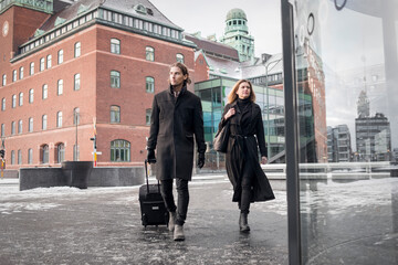 Woman and man with suitcase walking through city